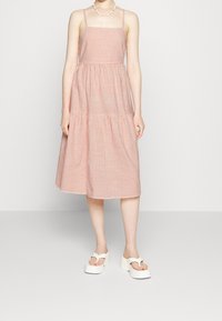 Raidallinen midi-mekko, jossa on ohuet olkaimet, vyötäröä korostava leikkaus ja kerrostettu hame. Värit sisältävät punaisen ja valkoisen. Yhdistettyinä paksupohjaisiin valkoisiin sandaaleihin.