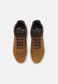Brązowe skórzane sneakersy o gładkim wykończeniu, ciemnobrązowe sznurowadła, teksturowane akcenty, okrągły czubek oraz kontrastowa biała gumowa podeszwa.