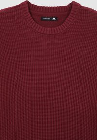 Sweater bordeaux realizzato in tessuto a maglia testurizzato. Presenta un collo a giro e polsini a costine. L'etichetta indica la taglia XL.
