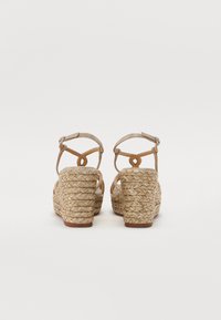 Sandales à talon compensé beige avec un talon en jute tressé, des brides de cheville réglables et une semelle intérieure texturée. Caractéristiques d'un dessus en cuir lisse au design minimaliste.