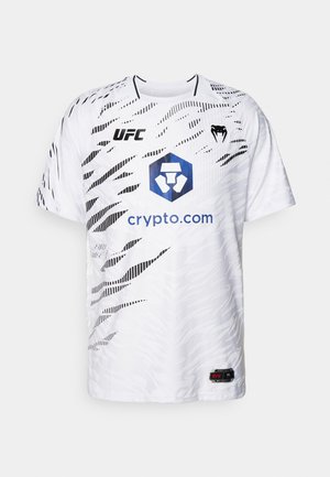 Hvit kortermet skjorte med et grafisk svart mønster. Viser UFC-logoen og en blå heksagonal logo med teksten "crypto.com" på forsiden.