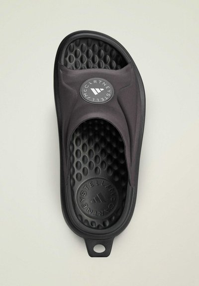 Svart slide-sandal med en slät ovandel, cirkulär logotyp på remmen och en texturerad fotbädd med upphöjda prickar för grepp och komfort.