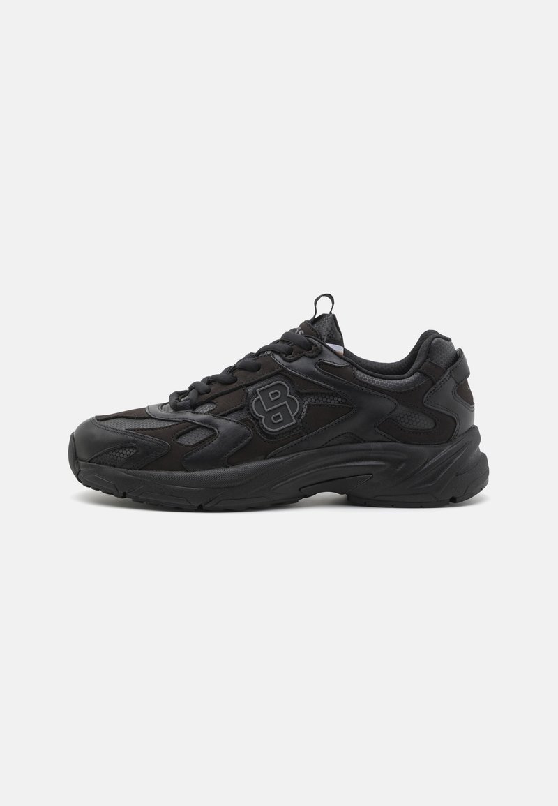 Baskets de sport noires avec semelle texturée, fermeture à lacets et logo stylisé "B" sur le côté, sur fond blanc uni.