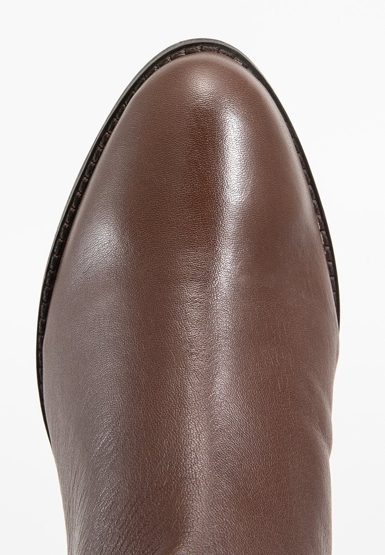 Close-up of the smooth, polished brown leather toe of a classic men's dress shoe with detailed stitching along the sole edge.