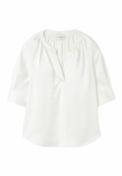 Blusa blanca de algodón con un corte relajado, escote en V y mangas cortas. Presenta detalles fruncidos cerca del escote y una textura suave.