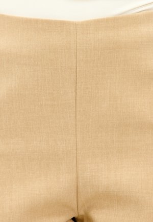Pantalones beige con una tela texturizada y tejida. Presentan una cinturilla suave y una costura vertical cosida en el centro de la parte trasera.