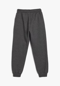Pantalones jogger de forro polar gris oscuro con cinturilla elástica y tobillos ajustados, colocados planos sobre un fondo blanco.