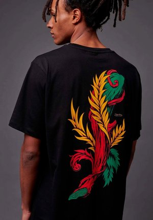 Zwarte t-shirt met een grote kleurrijke graphic op de achterkant, met gestileerde bladeren in rood, groen en geel en draaiende takken.