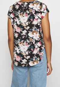 Blomstret bluse med sort baggrund, korte ærmer, buet kant og lynlåsdetalje på ryggen. Har farverige blomsterprint.