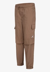 Brown cargo pants with elastic waistband and cuffs, side pockets, and a white Jumpman logo on the right thigh pocket.
