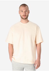 Short-sleeve, crew neck t-shirt in soft beige fabric. Features a relaxed fit and a small logo detail near the hem.