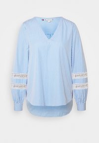 Blusa de manga larga de rayas verticales en azul y blanco con escote en V y bandas de encaje en las mangas bordadas con "HILFIGER".