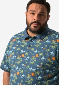 Modrá polo košile s límečkem; má multikolorový potisk palem, velbloudů a pyramid v zelené, oranžové a bílé barvě.