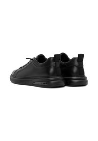 Zwarte leren sneakers met een ronde neus, vetersluiting, gevoerde kraag en een rubberen zool met een zichtbare luchtkussenunit.