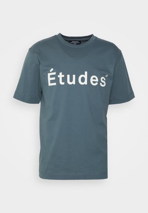 T-shirt bleu-vert à manches courtes avec le texte blanc "Études" sur la poitrine et un col rond, présenté sur un fond uni.