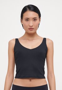 Black ribbed crop top with a v-neckline, fitted design, and thin straps. Smooth texture with vertical lines, suitable for layering.