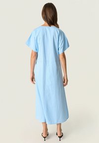 Svetlomodré, voľné maxi šaty s krátkymi rukávmi a rovným strihom, so hladkou textúrou a minimalistickým dizajnom.