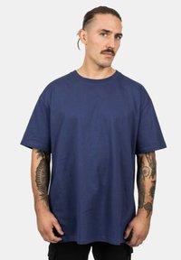 Navyblauwe katoenen T-shirt met korte mouwen en een ronde hals, met een gladde textuur en een comfortabele pasvorm. Zichtbare tattoos op de armen.