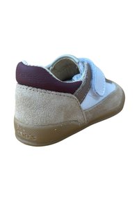 Zapato de niño pequeño en marrón, beige y blanco con cinta de Velcro, suela texturizada y cuello acolchado, mostrado desde un ángulo trasero.