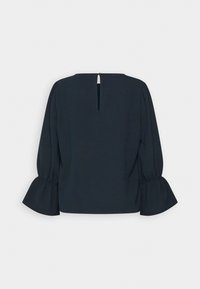 Blouse noire à manches longues avec fermeture goutte d'eau dans le dos et poignets évasés froncés aux poignets sur fond blanc.
