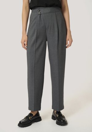 Grijze hooggetailleerde op maat gemaakte broek met twee knopen in de taille, rechte pijpen, gedragen met zwarte loafers met gouden gespdetail.