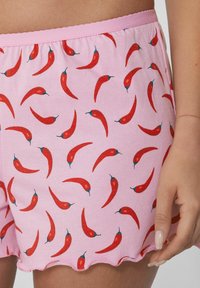 Roze katoenen shorts met een patroon van rode chilpepers op de stof. De zoom heeft een gegolfd ontwerp.