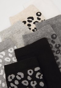Ett set av mönstrade strumpor i beige, grå och svart. Har olika leopardtryck och enfärgade partier med en mjuk textur och ribbade mudd. 
