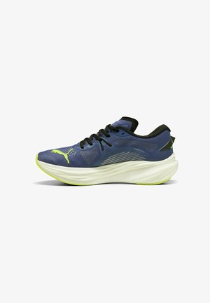 Scarpa atletica blu con tomaia in mesh testurizzato, lacci neri e una intersuola bianca e curvata. Presenta un accento verde e un logo sul lato.