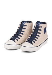 Vysoké tenisky s béžovou texturovanou tkaninou, námořnickými akcenty, bílou gumovou podrážkou a kulatou špičkou. Mají námořnické tkaničky a logo na boku.