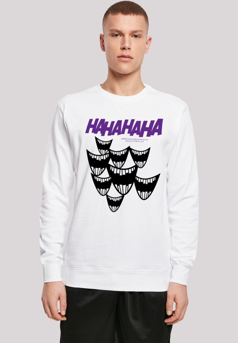 Bílé mikina s výrazným fialovým textem "HAHAHAHA" a grafikou černých stylizovaných usmívajících se obličejů. Dlouhé rukávy s žebrovanými manžetami.