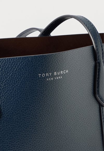 Bolsa de mão em couro azul marinho com uma superfície texturizada, apresentando duas alças e um logótipo metálico com a inscrição "TORY BURCH NEW YORK."