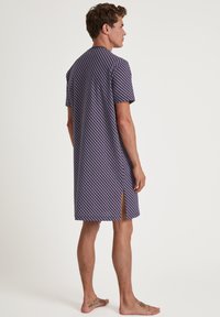 Short-sleeve nightgown in navy blue with a geometric pattern in red and white; features a side slit and a relaxed fit. Soft fabric texture.