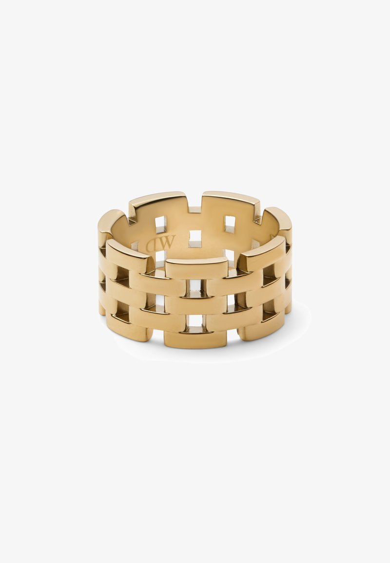 Auksinis žiedas su tarpusavyje persipynusiu dizainu, turintis kvadratines išpjovas ir lygiu paviršiumi. Forma plati ir suapvalinta, demonstruojanti metalinį blizgesį.