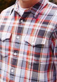 Rood, marineblauw en wit geruit flanellen overhemd met een button-down kraag, twee borstzakken en witte knopen. Zachte textuur, casual ontwerp.