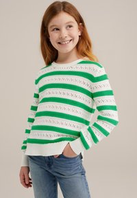 Vit tröja med gröna ränder, strukturerad stickning, med öppna mönster. Långa ärmar med ribbade mudd. Kombinerad med blå jeans.