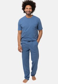 Sininen puuvillainen lyhythihainen paita, jossa on rintatasku, yhdistettynä matching kevyisiin naruhousuihin. Pehmeä rakenne, rento istuvuus.