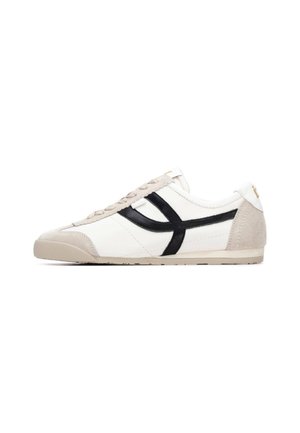 Zapatilla deportiva de cuero blanco con detalles en ante negro y beige, suela plana, cierre de cordones y costuras decorativas a lo largo de los laterales.
