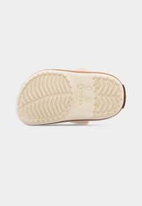 Σόλα μπεζ παπουτσιού Crocs που δείχνει το μοτίβο του πέλματος, την ένδειξη μεγέθους 7 και το λογότυπο των Crocs σε απλό λευκό φόντο.