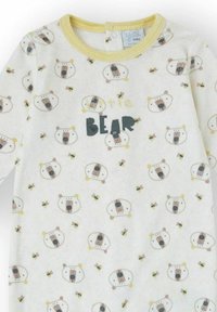 Body de manga larga para bebé en tela blanca con detalles amarillos, con un dibujo de un oso y el texto "Pequeño Oso" en negro. Textura suave.