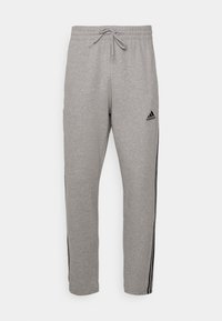 Grå sweatshirtbyxor med elastisk midja och dragsko. Har svarta sidosträck och en Adidas-logotyp på vänster lår.