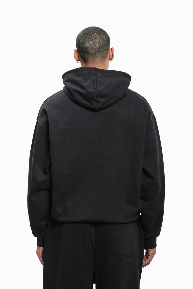 Sudadera negra con un corte relajado, hecha de una tela suave. Presenta una capucha con cordón y puños acanalados. Diseño minimalista sin logotipos.