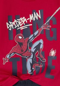 Red cotton T-shirt featuring a graphic of Spider-Man in a dynamic pose, with white and navy text reading "HANG TIME" and a small spider icon.