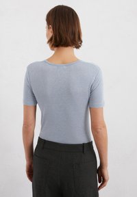 T-shirt azzurro chiaro a maniche corte con scollo rotondo, taglio aderente e texture soffice, abbinato a pantaloni scuri con tasche laterali.