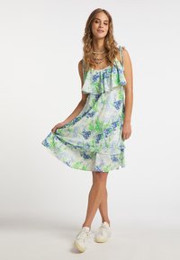 Blumenmuster, ärmelloses Kleid in Hellblau und Grün, mit schichtigen Rüschen und einem fließenden Schnitt.