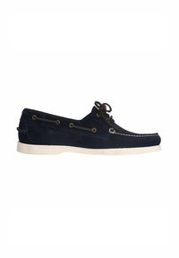 Marineblauwe suède bootshoe met een witte rubberen zool, voorzien van bruine lederen veters en metalen oogjes, gestructureerd ontwerp en contrasterende stiksels.