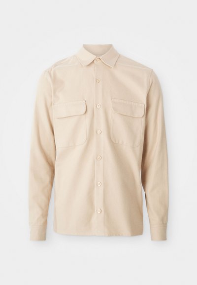 Kreemikas pikkade varrukatega särk, mis on valmistatud kudumiskangast, kahte rinna taskuga, terava kraega ja nööbiga eesmine sulgemine. Sile tekstuur.