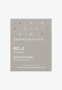 Emballage de bougie parfumée gris clair avec des motifs géométriques en relief. Le texte indique "SKANDINAVISK RO Tranquillité" ainsi que des détails sur la taille et le matériau.