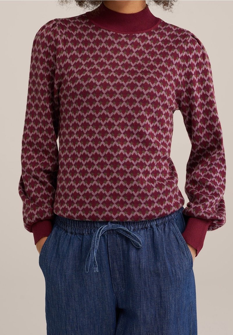 Burgundyröd stickad tröja med ett diamantmönster i ljusrosa och grönt, med rundad ribbad halsringning och elastiska ärmmuddar. Matchas med jeans.