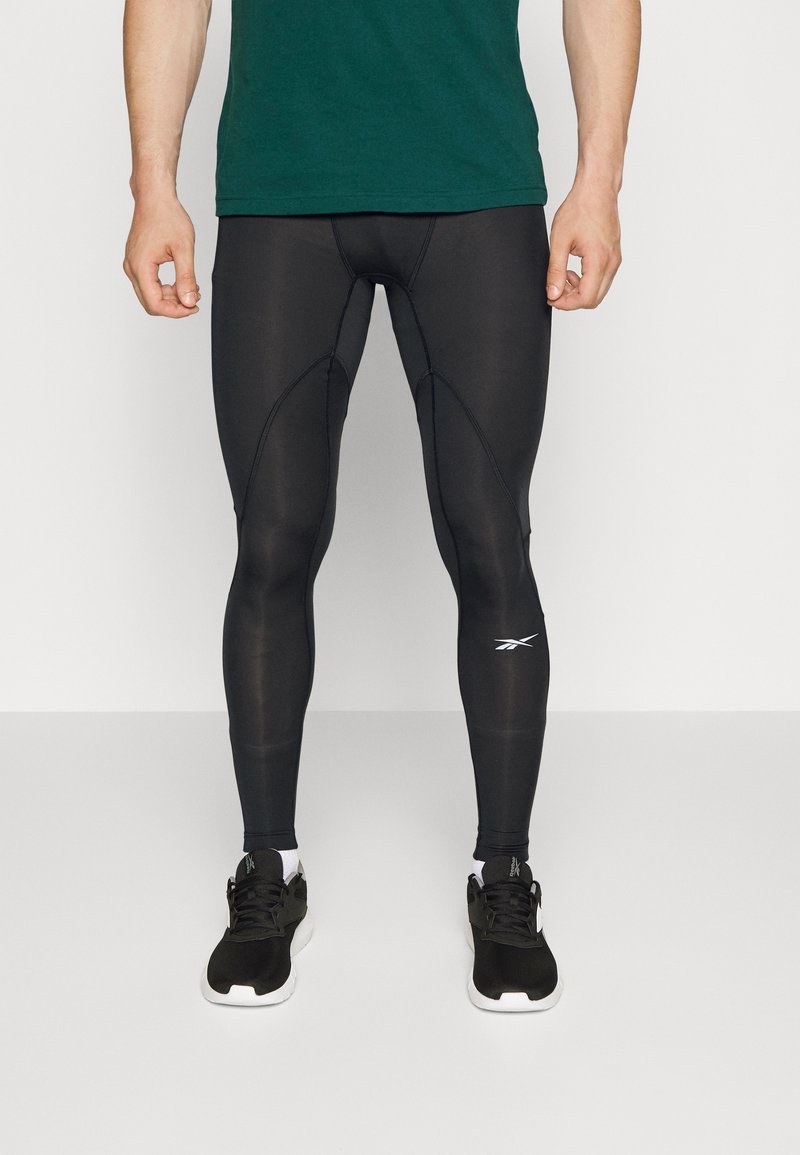 Svarta sportleggings i stretchigt, fukttransporterande material. Har en åtsittande design och en liten vit logotyp på nederdelen av benet.