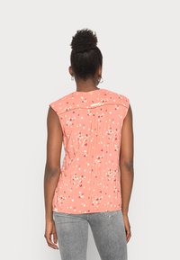 Top sem mangas de cor pêssego com padrão floral, pregas nas costas e decote arredondado, feito de tecido leve.